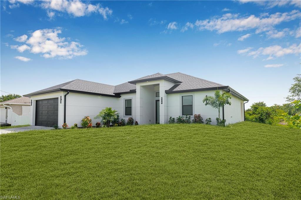 Prairie-style home featuring a front yard, stucco siding, driveway, and a garage