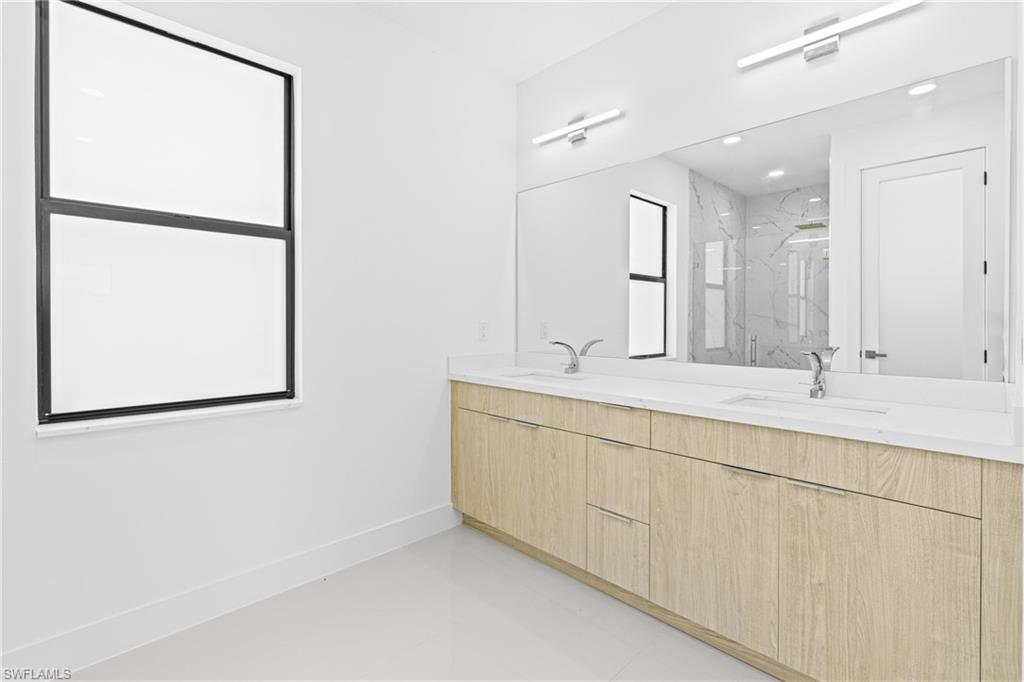 Full bathroom featuring double vanity and a marble finish shower