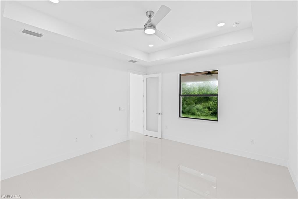 Spare room with a tray ceiling, recessed lighting, and ceiling fan