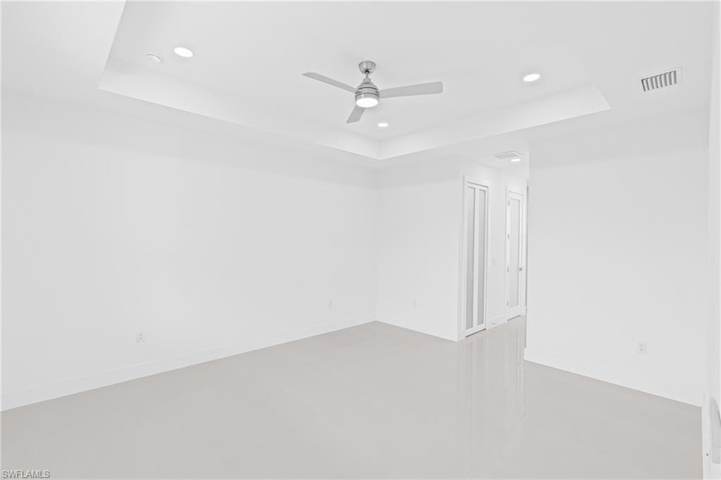 Unfurnished room featuring a raised ceiling, ceiling fan, and recessed lighting