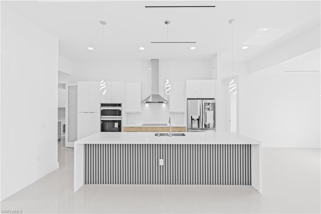 Kitchen featuring white cabinetry, modern cabinets, a spacious island, and stainless steel fridge with ice dispenser