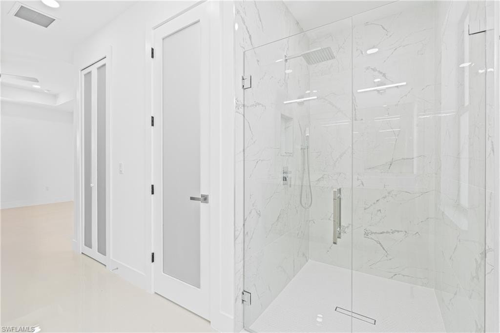 Bathroom with a marble finish shower and recessed lighting