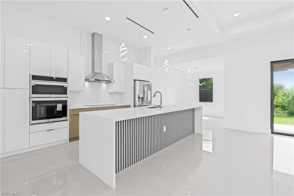 Kitchen featuring pendant lighting, white cabinetry, modern cabinets, stainless steel appliances, and light stone countertops