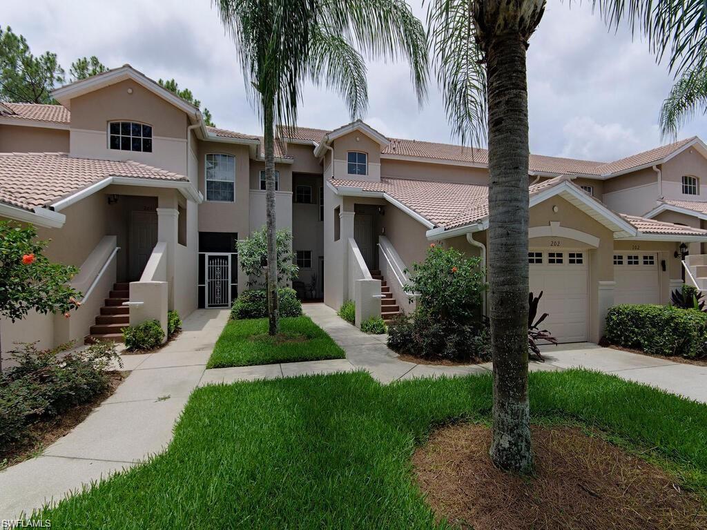 Mediterranean / spanish home featuring stucco siding, a tiled roof, a front yard, and driveway