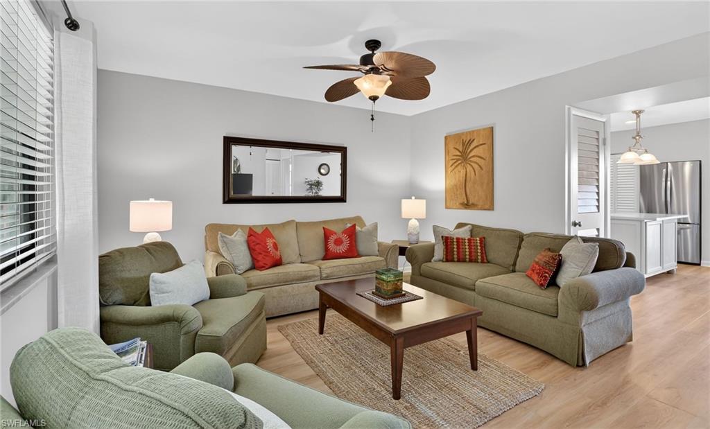 Living room featuring light wood finished floors, ceiling fan, and plenty of natural light