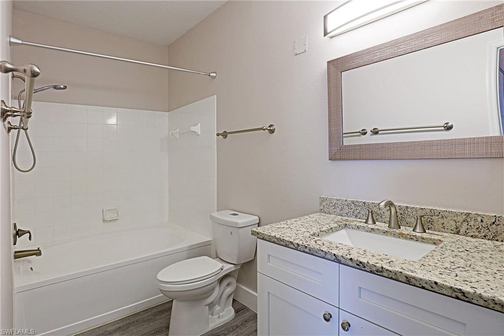 Full bathroom featuring vanity, tub / shower combination, and dark wood-type flooring