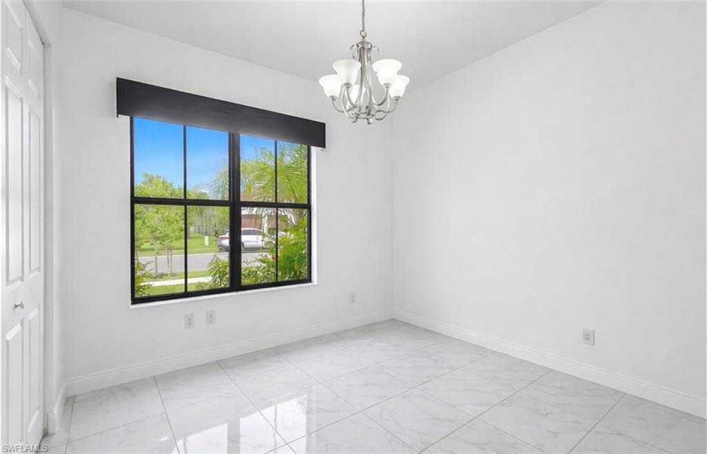 Spare room featuring a chandelier and light marble finish floors