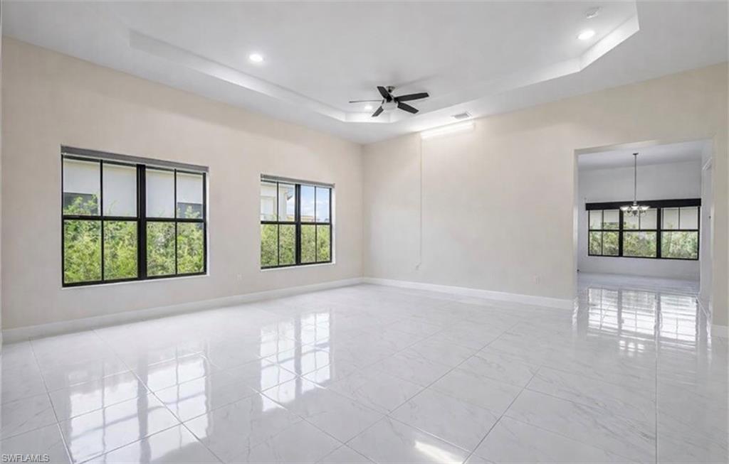 Empty room featuring a ceiling fan, a tray ceiling, and suspended lighting