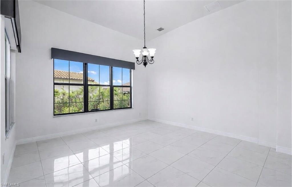 Empty room with suspended lighting, light tile patterned floors, and lofted ceiling