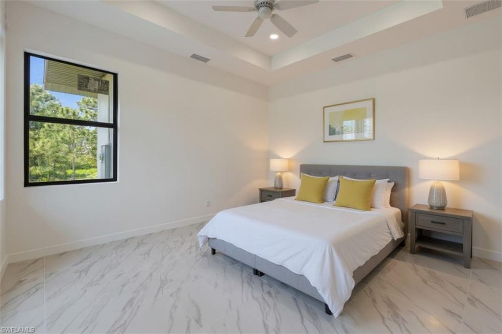 Bedroom featuring a raised ceiling, a ceiling fan, recessed lighting, and light marble finish floors