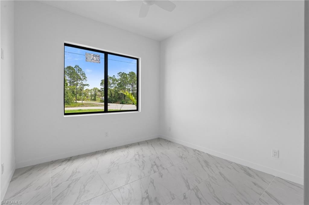 Unfurnished room featuring light marble finish floors and a ceiling fan