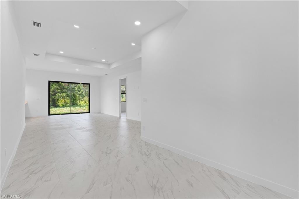 Spare room featuring light marble finish floors, recessed lighting, and a tray ceiling