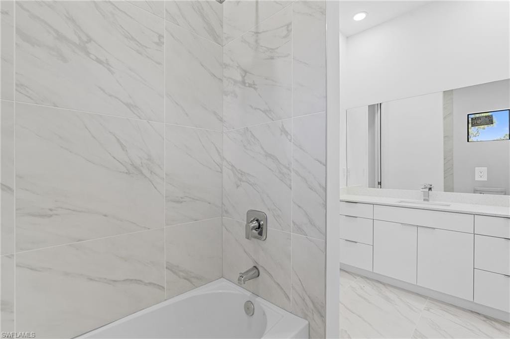 Bathroom featuring shower / washtub combination, vanity, and recessed lighting