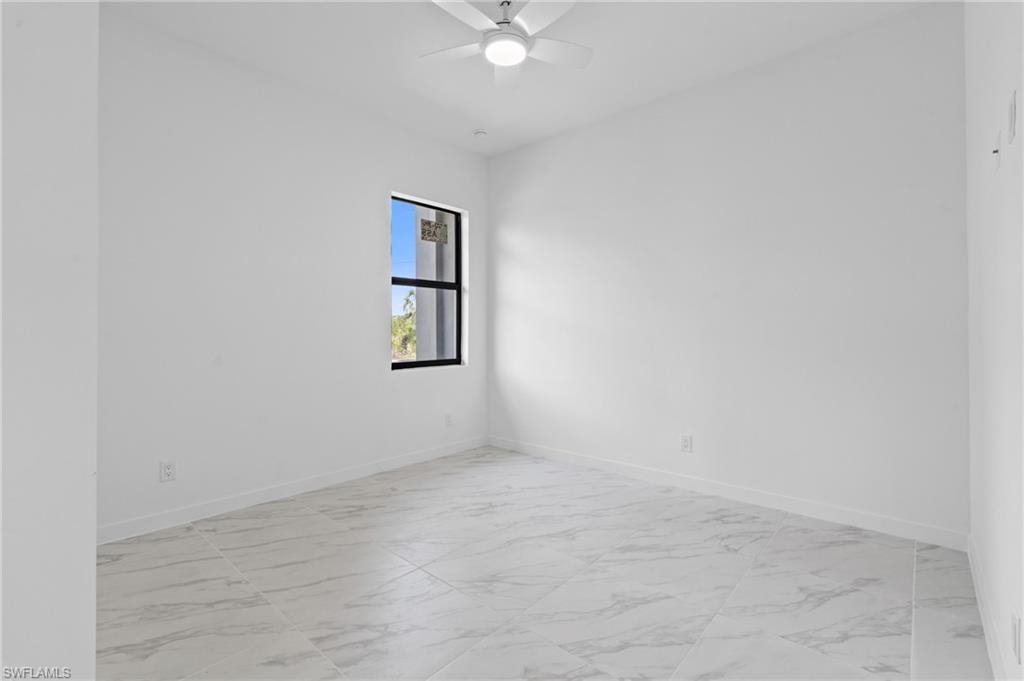 Empty room featuring light marble finish flooring and ceiling fan