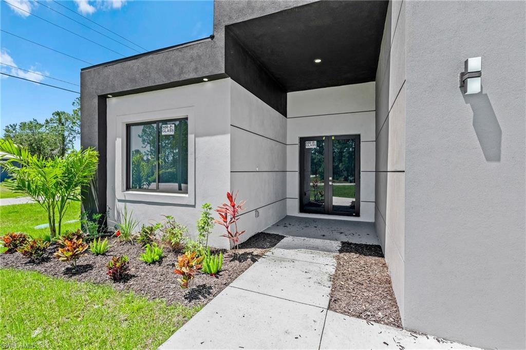 Entrance to property with stucco siding and a lawn