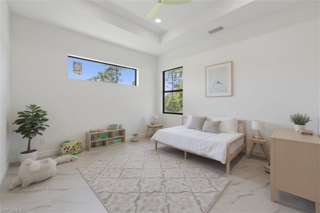 Bedroom featuring a ceiling fan, a tray ceiling, marble finish flooring, and recessed lighting