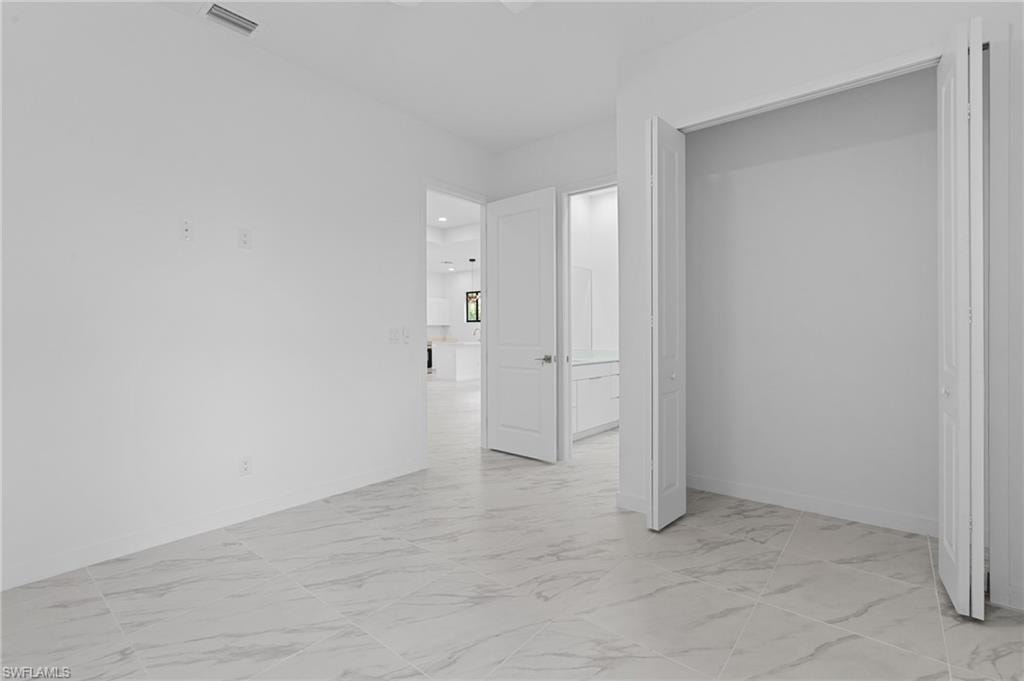 Unfurnished bedroom with light marble finish floors and a closet