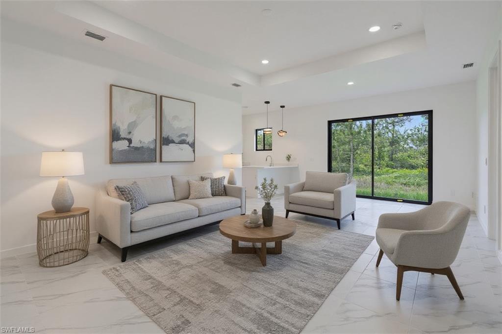 Living room featuring a tray ceiling, recessed lighting, and light marble finish floors