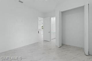 Unfurnished bedroom with light marble finish floors and a closet