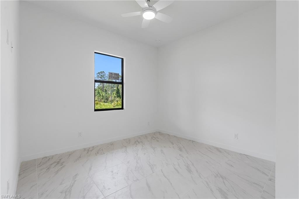 Spare room with light marble finish floors and a ceiling fan