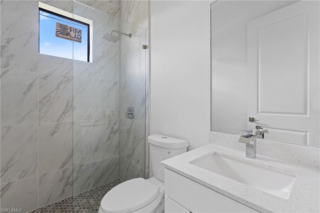 Full bath featuring a marble finish shower and vanity