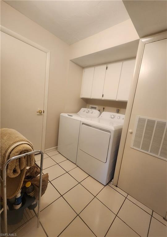 Laundry room featuring washing machine and dryer, cabinet space, and light tile patterned floors