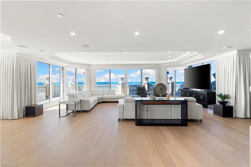 Living room featuring a tray ceiling, light wood-type flooring, and floor to ceiling windows