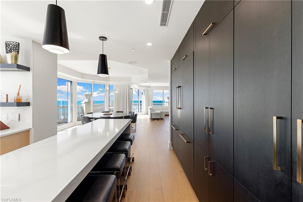 Kitchen with a breakfast bar, hanging light fixtures, light wood-style flooring, modern cabinets, and a raised ceiling