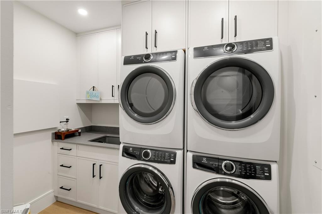 Laundry room featuring cabinet space, light wood finished floors, and recessed lighting