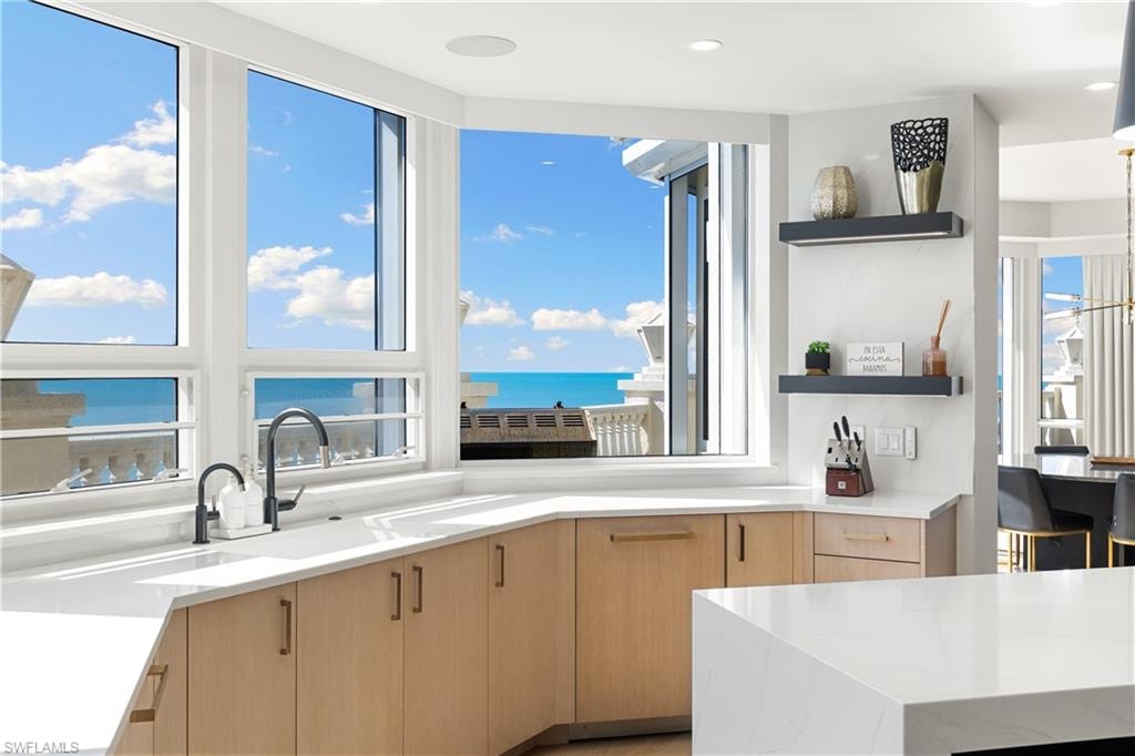 Kitchen with light wood finish cabinetry, light stone countertops, open shelves, modern cabinets, and recessed lighting