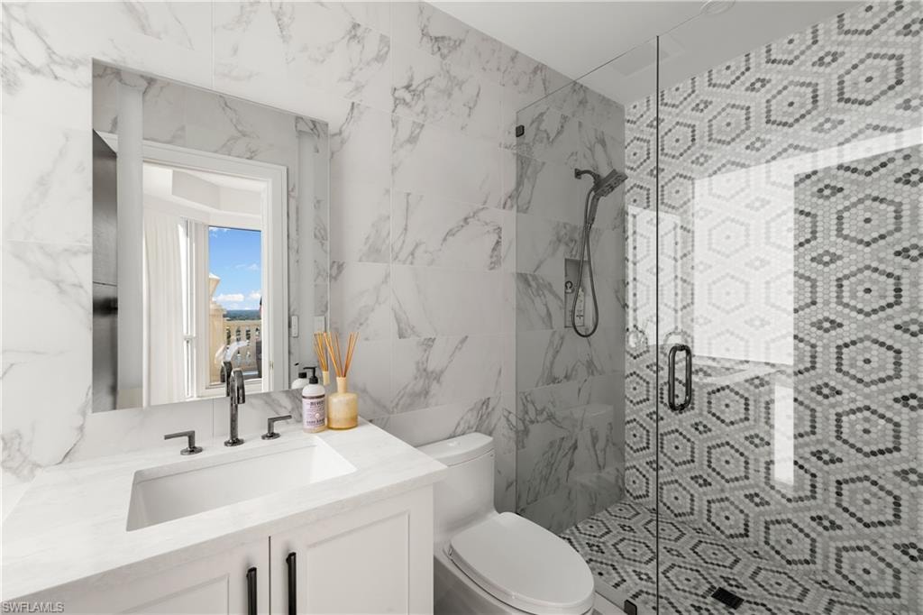 Full bathroom with a shower stall, vanity, and tile walls
