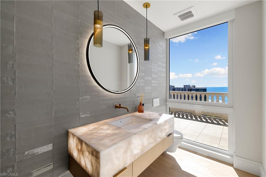 Half bathroom featuring tile walls, vanity, a water view, and wood finished floors