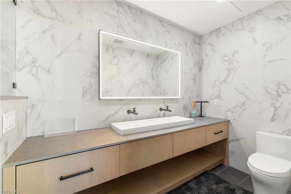 Bathroom with tile walls, vanity, and dark tile patterned floors