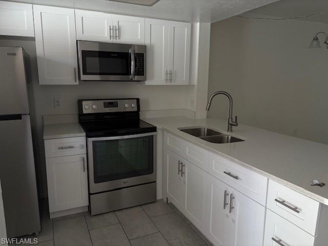 Kitchen with stove, refrigerator, light tile patterned floors, white cabinetry, and light countertops