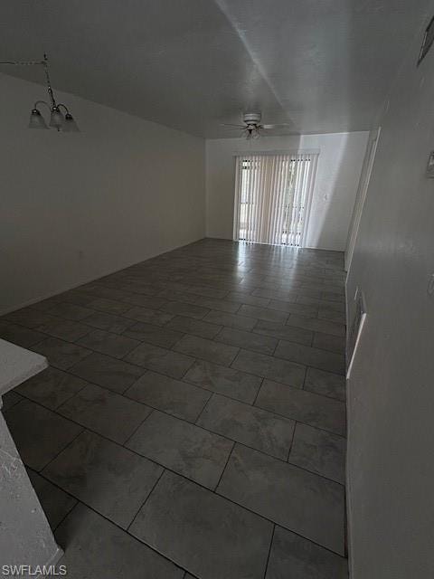 Spare room featuring ceiling fan and a chandelier