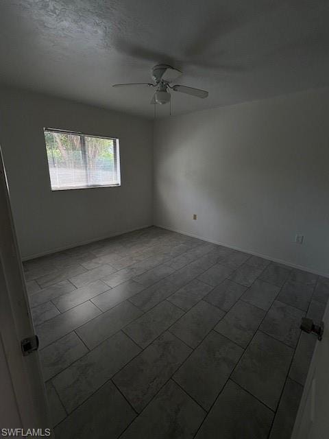 Empty room featuring ceiling fan and baseboards