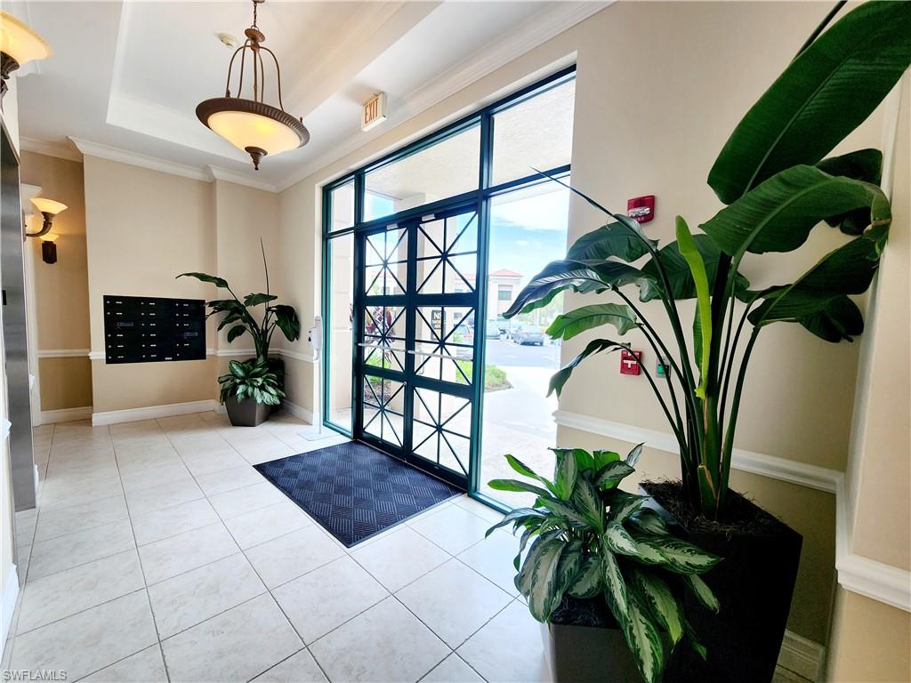 Entrance foyer with mail area, a tray ceiling, tile patterned floors, and crown molding