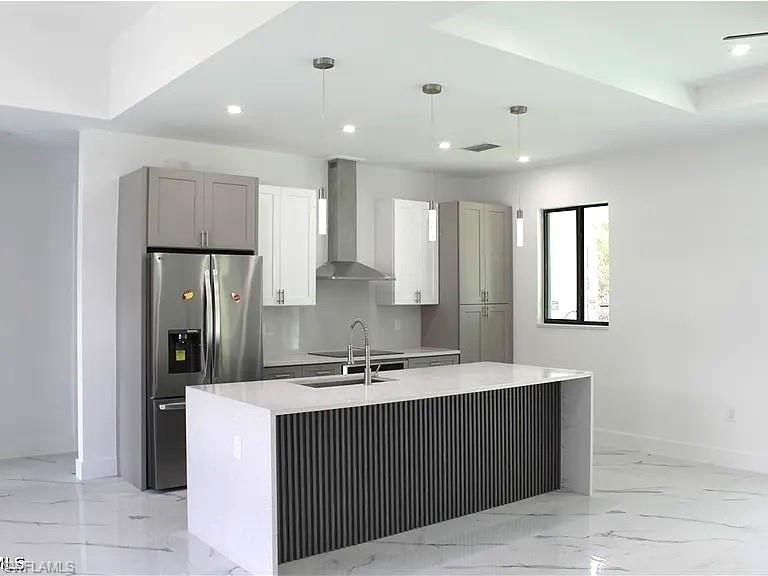 Contemporary kitchen featuring a large waterfall island with a slatted accent panel, white countertops, and a stainless steel range hood