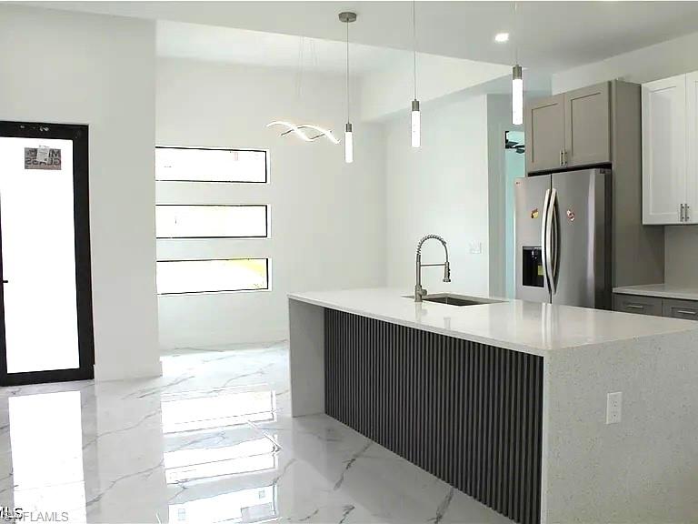 Modern kitchen island featuring a waterfall quartz countertop, integrated stainless steel sink, and a contemporary fluted panel base