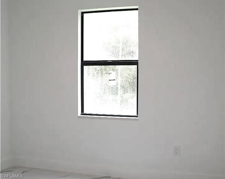 Bright interior space featuring a vertical window with black framing, white walls, and light-toned flooring
