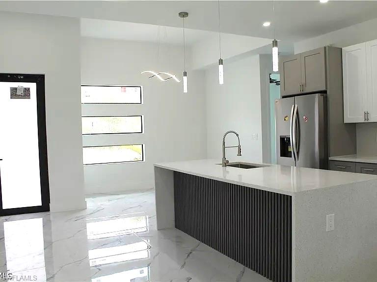 Modern kitchen featuring a waterfall island with a quartz countertop, integrated sink, and contemporary pendant lighting