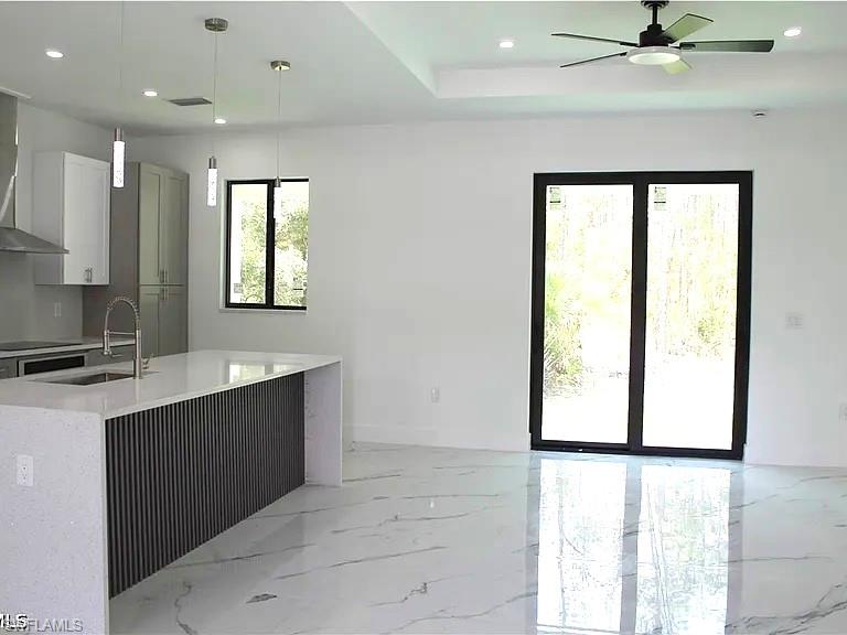 Spacious living area featuring polished tile flooring, a contemporary kitchen island with a fluted panel base and light-toned countertop, and recessed ceiling lighting