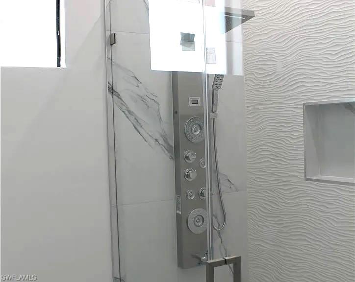 Shower featuring a multi-function panel, clear glass enclosure, a rainfall showerhead, and a handheld spray
