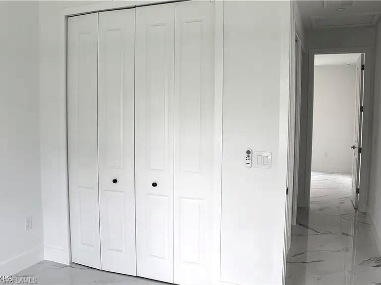 White bifold closet doors with black hardware, complemented by white walls and white baseboards