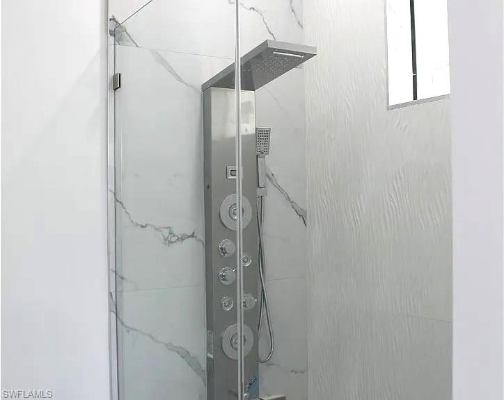 Walk-in shower with a frameless glass enclosure and a multi-function shower panel