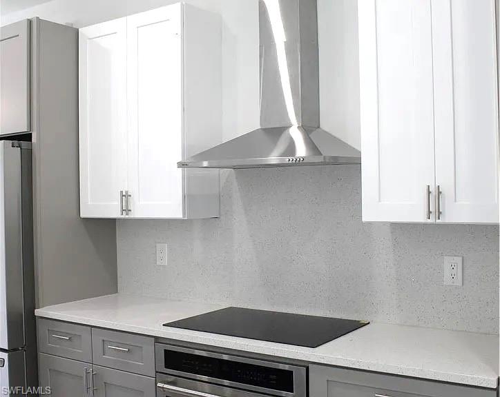 Modern kitchen featuring two-tone cabinetry with white upper and gray lower cabinets, light-toned countertops, and a matching full-height backsplash