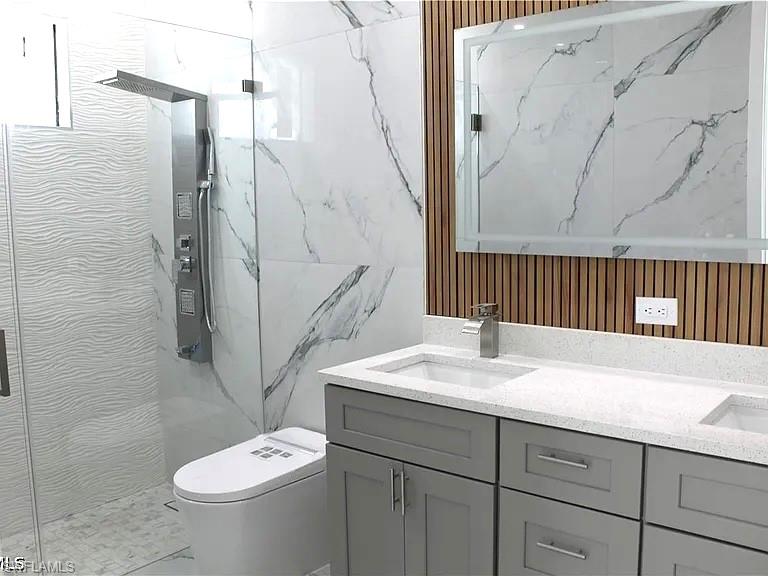 Bathroom featuring a double vanity with light gray cabinetry, light speckled countertops, and undermount sinks