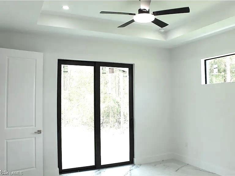 Bright interior space featuring a tray ceiling, recessed lighting, and a modern ceiling fan