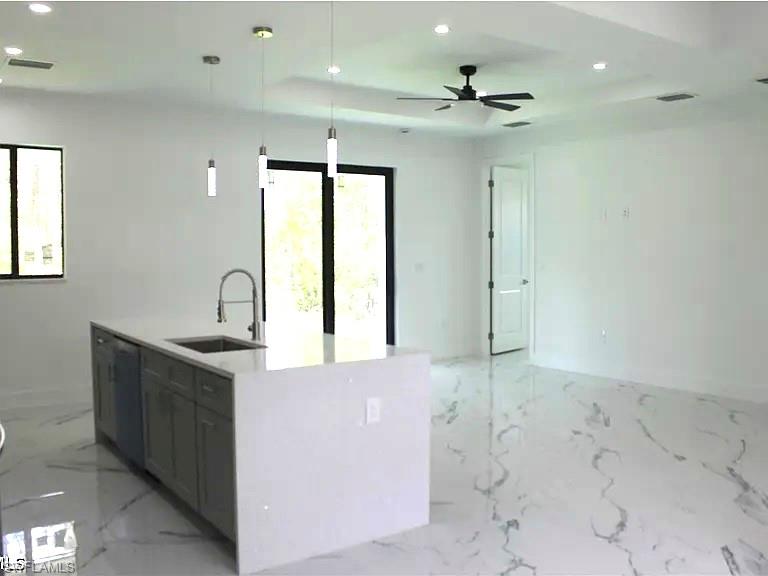 Spacious interior featuring a kitchen island with integrated sink, stainless steel faucet, and pendant lighting