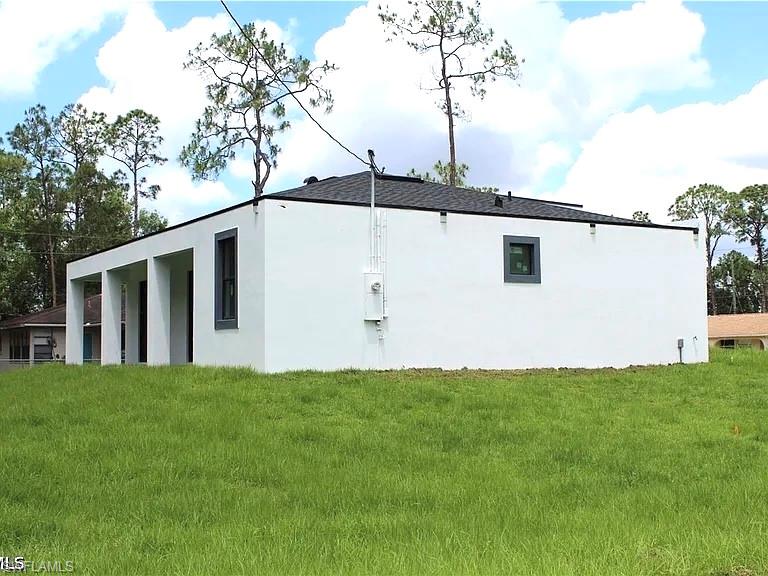 Contemporary exterior with a stark white facade, dark-framed windows, and a black shingle roof